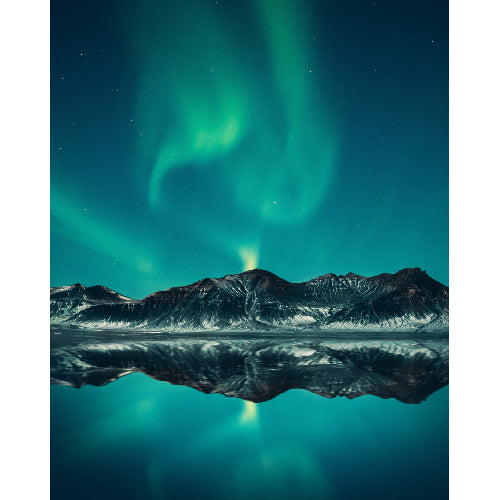 Noorderlicht (aurora borealis) dansend boven een bergketen met reflectie in een rustig meer.