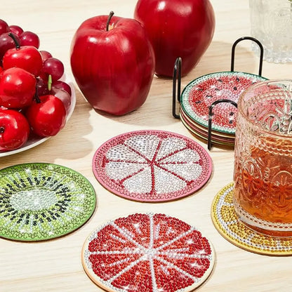 Fruitvormige diamond painting onderzetters, inclusief kiwi en grapefruit, met een glas sap op een tafel.