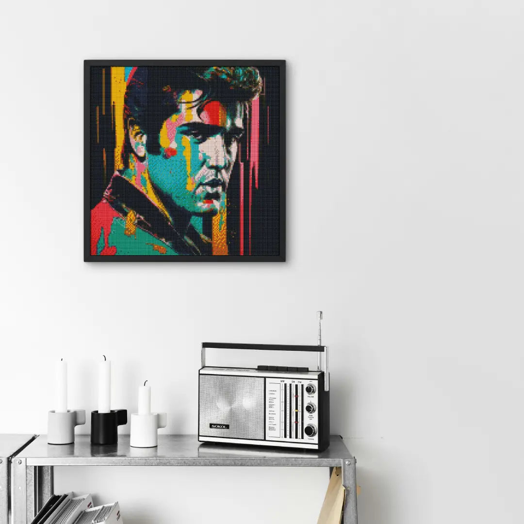 Ingelijst diamond painting van een kleurrijk portret van Elvis Presley, opgehangen boven een metalen plank met een retro radio en kaarsen.