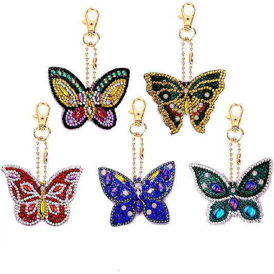 Collectie van vijf kleurrijke vlinder diamond painting sleutelhangers, elk uniek ontworpen met levendige kleuren en gedetailleerde patronen.